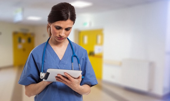 A clinician looks at a mobile device on the ward