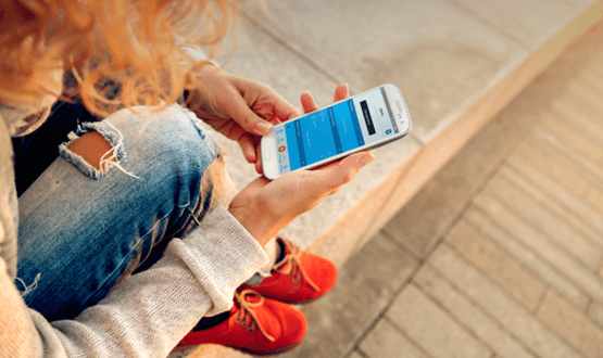 A young woman looking at a text reminder on her mobile phone