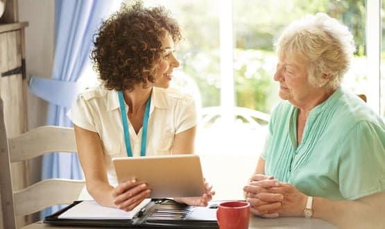 a care worker makes a house call to a senior client at her home